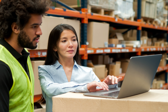 Vrouw en man die naar een laptop kijken in een warehouse