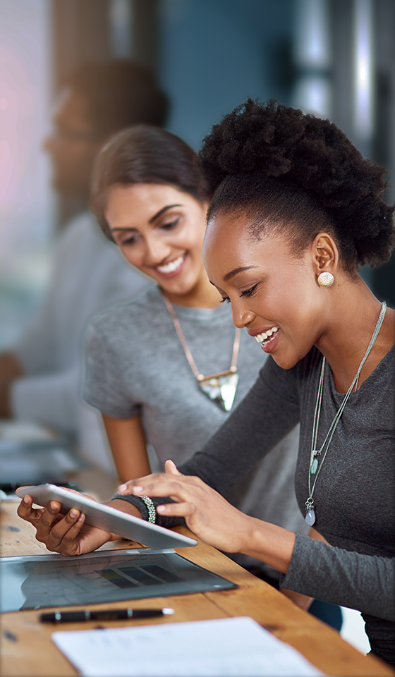 Twee vrouwen die glimlachen en naar een iPad kijken