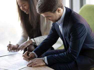 Two people signing paperwork