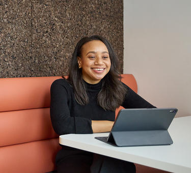 Prologis employee smiling at a tablet in an open office space